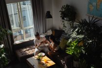 Uomo scattare foto di donna che ha cibo con il telefono cellulare in soggiorno a casa — Foto stock