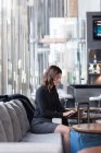 Donna d'affari che utilizza tablet digitale sul divano in hotel — Foto stock
