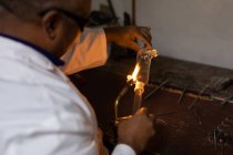 Рабочий мужчина с помощью сварочной горелки на стекольном заводе — стоковое фото