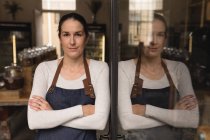 Portrait of female staff standing with arms crossed in supermarket — Stock Photo
