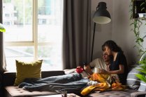 Casal usando telefone celular enquanto toma café na sala de estar em casa — Fotografia de Stock