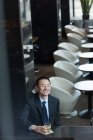 Uomo d'affari sorridente che beve whisky al bancone del bar in hotel — Foto stock