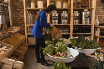 Mulher colocando vegetais em saco de compras no supermercado — Fotografia de Stock