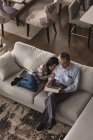 Дід і онука використовують цифровий планшет на дивані у вітальні вдома — стокове фото
