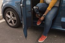 Низкая часть женщины-инвалида, завязывающей шнурки, сидя в машине — стоковое фото