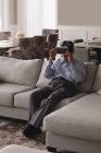 Uomo anziano utilizzando auricolare realtà virtuale sul divano in soggiorno a casa — Foto stock