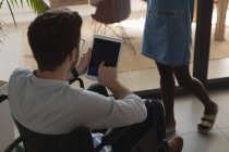 Rear view of handicap executive using digital tablet in office — Stock Photo