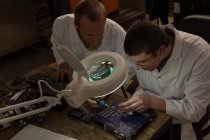 Engenheiros de robótica montando placa de circuito na mesa no armazém — Fotografia de Stock