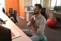 Ejecutivo de negocios haciendo yoga en el escritorio en la oficina - foto de stock