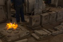 Sección baja de la calefacción del trabajador fundición de metal con antorcha llameante - foto de stock