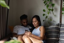 Пара с помощью мобильного телефона на диване в гостиной на дому — стоковое фото