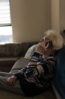 Старша жінка розмовляє по мобільному телефону у вітальні вдома — стокове фото