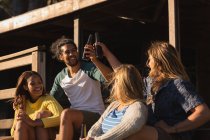 Fröhliche Gruppe von Freunden prostet Bierflasche auf Kabine zu — Stockfoto