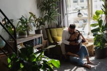 Casal usando telefone celular na sala de estar em casa — Fotografia de Stock
