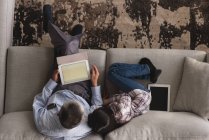 Накладний дід і онука використовують цифровий планшет на дивані у вітальні вдома — стокове фото
