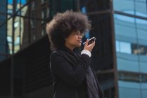 Young woman talking on mobile phone in city — Stock Photo