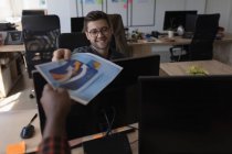 Sorrindo executivo masculino dando gráfico para colega no escritório — Fotografia de Stock