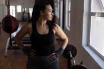 Young female boxer looking through window in fitness studio — Stock Photo