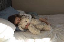 Mädchen schläft mit Teddybär im Schlafzimmer zu Hause — Stockfoto