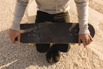 Aus der Vogelperspektive: Frau sitzt mit Skateboard am Strand — Stockfoto