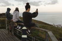Seitenansicht von Skateboardern, die am Aussichtspunkt auf einem Geländer sitzen — Stockfoto