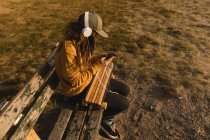 Молода жінка слухає музику на мобільному телефоні на пляжі — стокове фото
