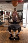 Entrenadora que ayuda a la boxeadora a levantar pesas en el gimnasio - foto de stock