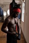 Jovem boxeador masculino vestindo envoltório de mão em estúdio de fitness — Fotografia de Stock