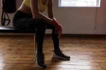 Low section of female boxer relaxing in fitness studio — Stock Photo