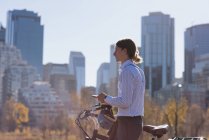 Человек с мобильным телефоном во время прогулки на велосипеде по городу в солнечный день — стоковое фото