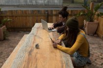 Patinadores jóvenes que utilizan dispositivos multimedia en la cafetería al aire libre - foto de stock