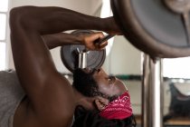 Close-up of male boxer exercising with bench press barbell in fitness studio — Stock Photo