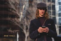 Человек с мобильного телефона во время прогулки по улице в городе — стоковое фото