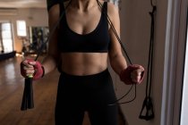 Seção média de boxeador feminino de pé com pular corda no estúdio de fitness — Fotografia de Stock