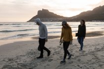 Молодые скейтбордисты прогуливаются по пляжу на закате — стоковое фото