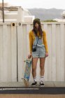 Belle skateboarder femme debout avec skateboard sur rampe de skateboard — Photo de stock
