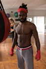 Retrato de boxeador masculino sin camisa de pie en el gimnasio - foto de stock
