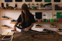 Jeune femme réparant skateboard dans l'atelier — Photo de stock
