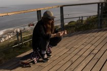 Junge Skateboarderin nutzt Handy an Beobachtungsstelle — Stockfoto