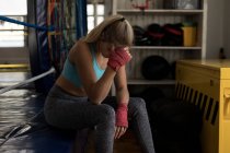 Boxeadora mujer cansada relajándose en el ring de boxeo en el gimnasio - foto de stock