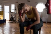 Tired female boxer relaxing in fitness studio — Stock Photo