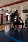 Boxer femminile che si prende una pausa nel ring di pugilato in palestra — Foto stock