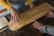 Close-up of skateboarders examining skateboard deck in workshop — Stock Photo
