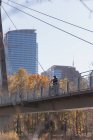 Вдумчивый человек, стоящий с велосипедом на мосту в городе — стоковое фото