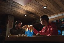 Jovens amigos brindam copos de cerveja no pub — Fotografia de Stock