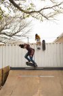 Young female skateboarder clicking photo while male skateboarder skating on skateboard ramp — Stock Photo