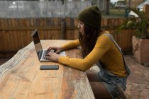 Красива жінка скейтбордистка використовує ноутбук у відкритому кафе — стокове фото