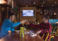 Amici felici brindare bicchieri di birra nel pub — Foto stock