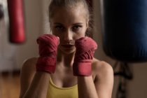 Portrait of female boxer forming hand fist in fitness studio — Stock Photo