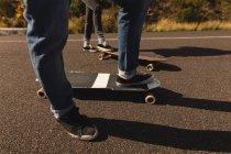 Низкая часть скейтбордистов, стоящих со скейтбордом на склоне в сельской местности — стоковое фото